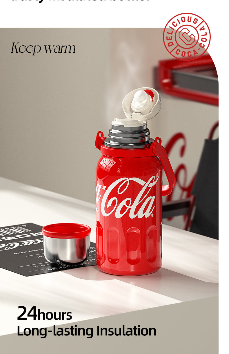 Red Coca-Cola thermos with a white lid on a surface, featuring text about insulation and a brand logo.