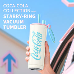 Coca-Cola tumbler with pink starry-ring design held by a hand against a blurred background