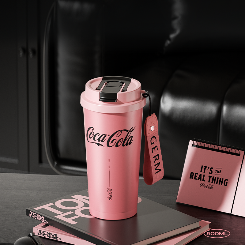 Pink Coca-Cola tumbler with a tag on a dark surface