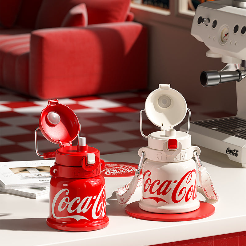 Coca-Cola-themed water bottles and coffee machine on a table with a red and white checkered floor in the background.