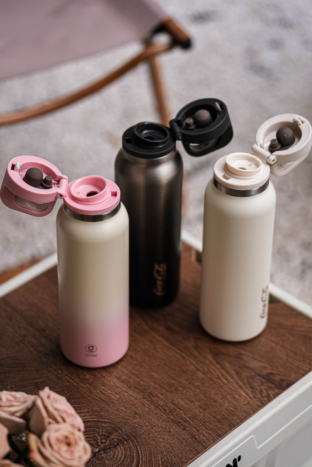 Three insulated bottles with different designs on a wooden surface.