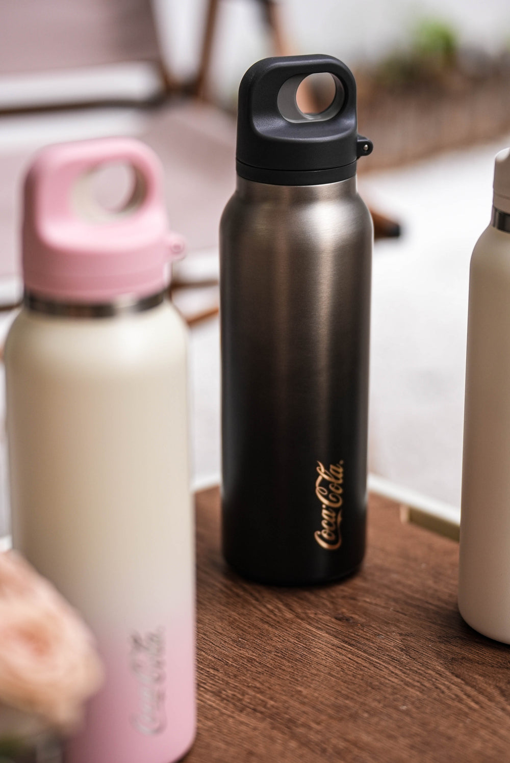 Three insulated bottles with different designs on a wooden surface.
