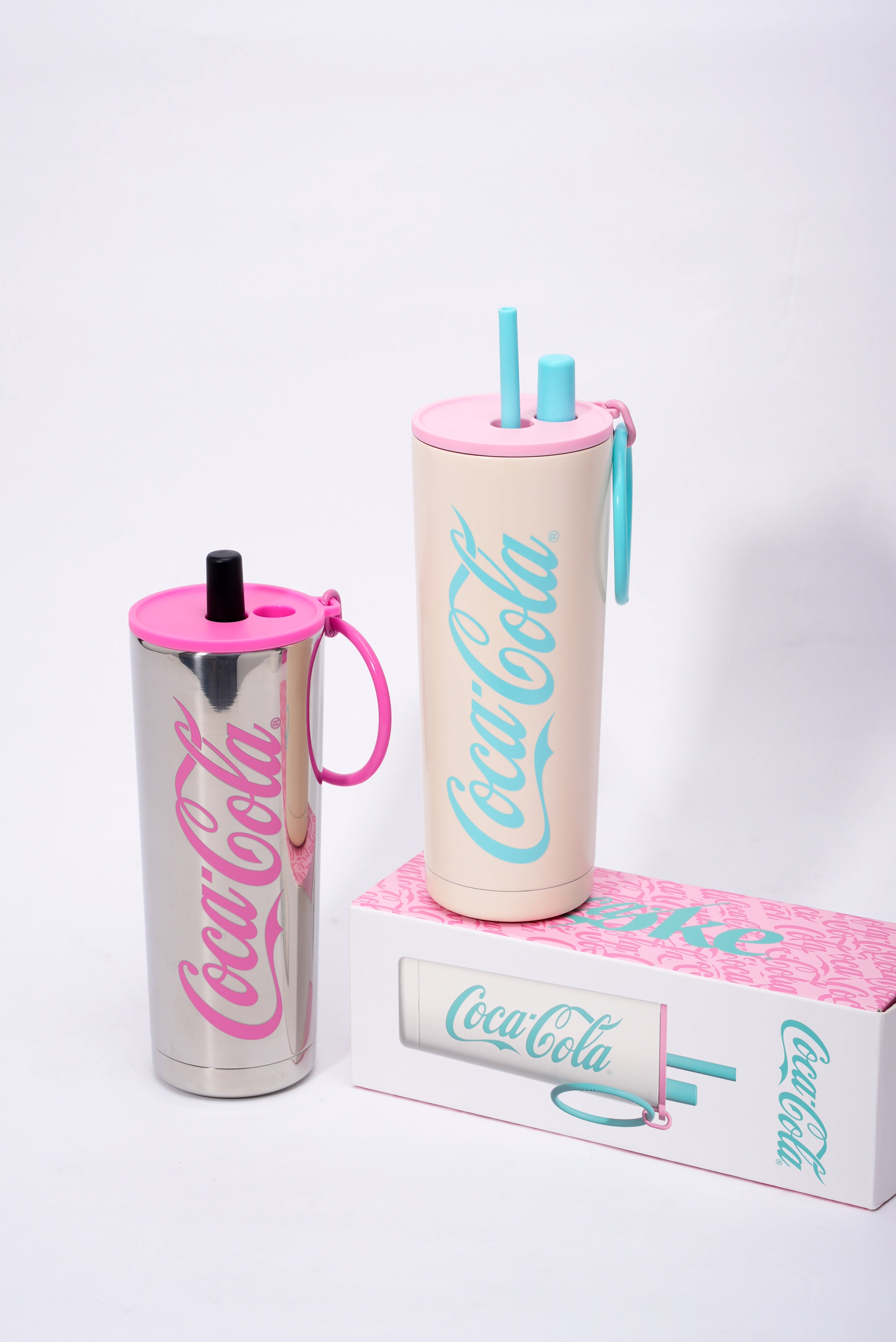 Two Coca-Cola tumblers with pink and blue accents on a white background