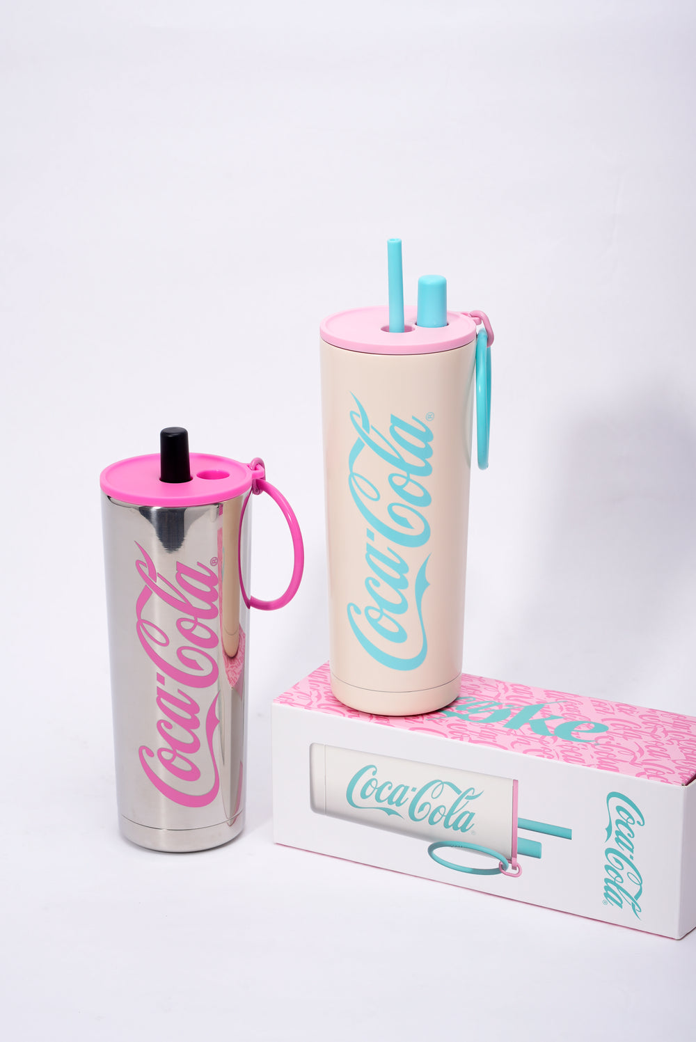Two Coca-Cola tumblers with pink and blue accents on a white background